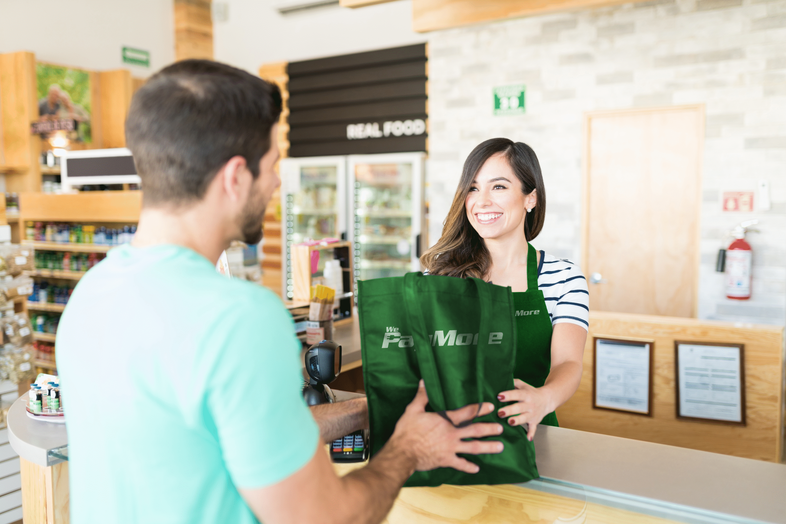 confident-female-cashier-giving-bag-young-man-checkout-counter-supermarket copy